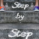 Two people walking up stairs step by step, symbolizing consistency and progress toward success.