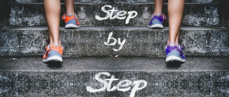 Two people walking up stairs step by step, symbolizing consistency and progress toward success.