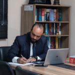 Focused man writing at a clean desk in a home office representing productivity and discipline.