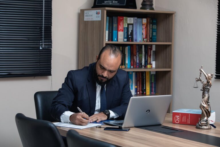Focused man writing at a clean desk in a home office representing productivity and discipline.