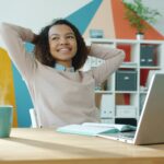 Woman smiling confidently while working from home, feeling focused and productive after simplifying her system.