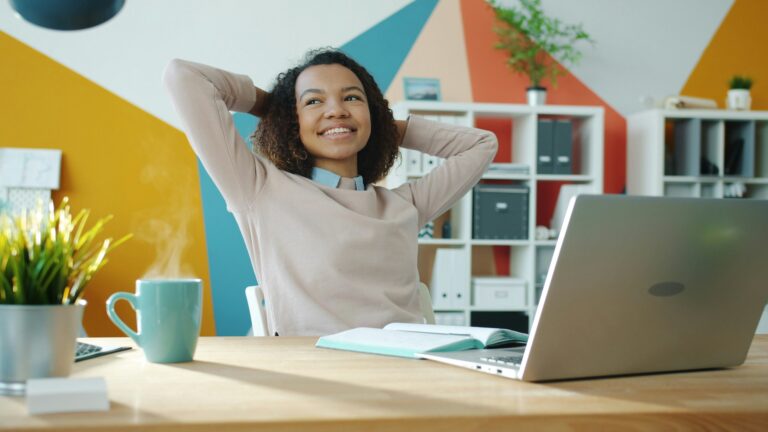 Woman smiling confidently while working from home, feeling focused and productive after simplifying her system.